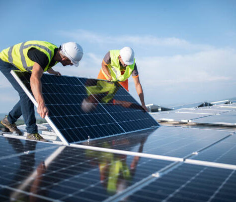Team of two engineers installing solar panels on roof.
