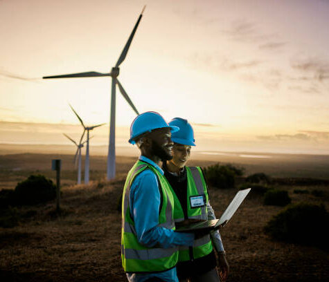 Laptop, farm and engineer team together at night for renewable energy, power and wind turbine. Electrician or technician man and woman in nature for electricity, eco and green environment maintenance